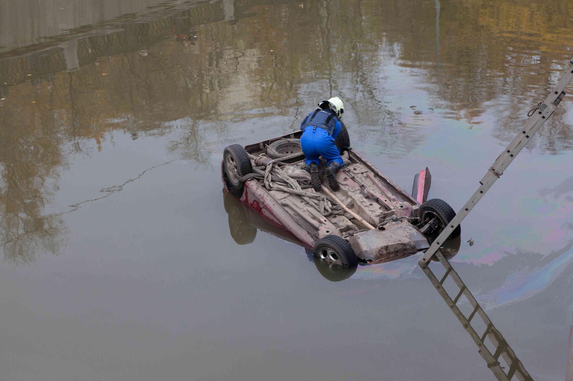 car fell into water and capsized. Rescuer attaches the rope.